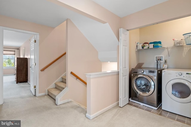 clothes washing area with carpet flooring, baseboards, washing machine and dryer, and laundry area