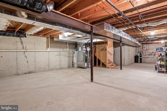 unfinished below grade area featuring stairway, heating unit, and water heater