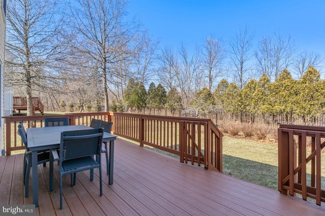 deck featuring outdoor dining area and a lawn