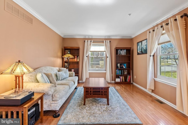 living area featuring wood finished floors, visible vents, and ornamental molding