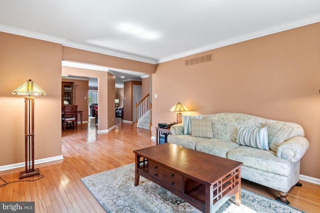 living area with visible vents, wood-type flooring, crown molding, baseboards, and stairs