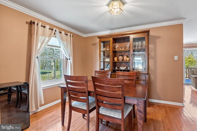 dining area featuring a healthy amount of sunlight, light wood-style flooring, and ornamental molding