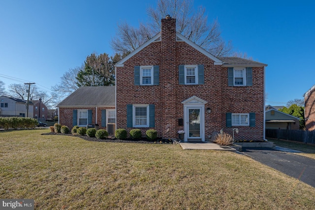 view of front facade with a front lawn, central AC unit, brick siding, and a chimney