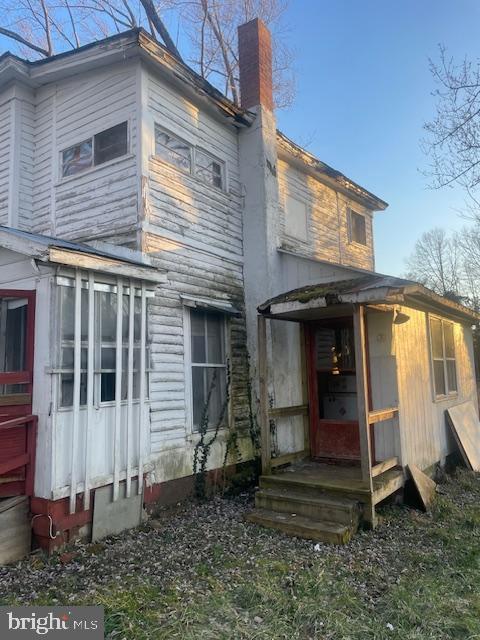 rear view of house with entry steps and a chimney