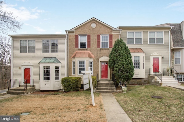 townhome / multi-family property with brick siding and a front lawn