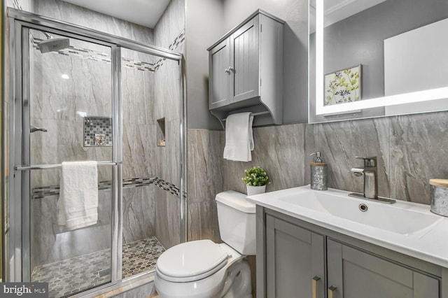 full bathroom with tile walls, a stall shower, toilet, and vanity