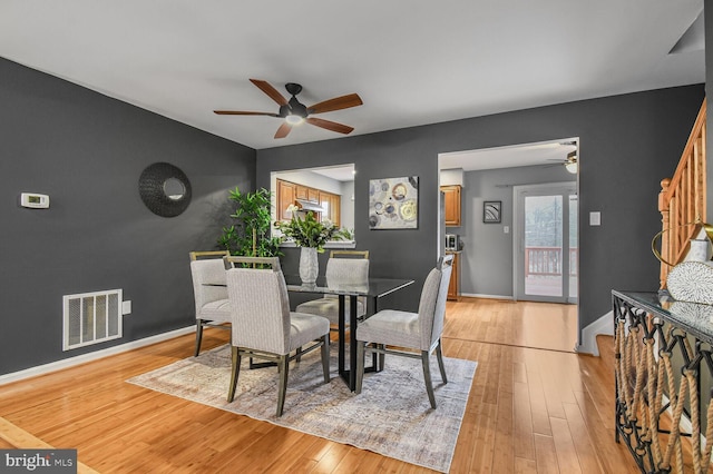 dining room with light wood-type flooring, baseboards, visible vents, and ceiling fan