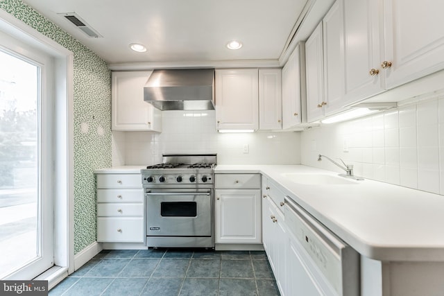 kitchen featuring visible vents, dishwasher, wall chimney exhaust hood, designer range, and a sink