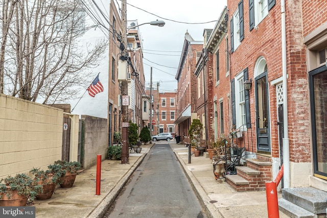 view of street featuring entry steps, curbs, traffic signs, sidewalks, and street lights