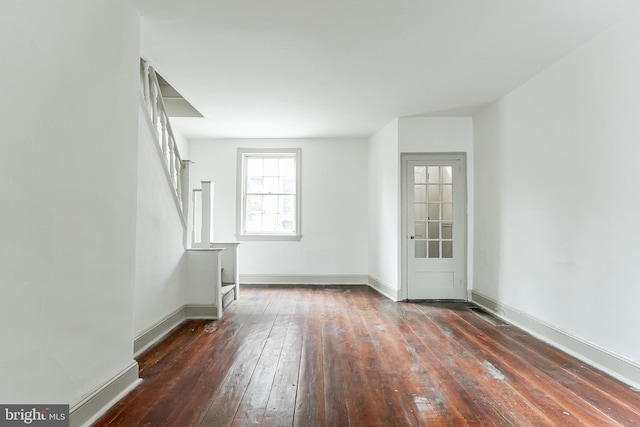 unfurnished living room with hardwood / wood-style floors and baseboards