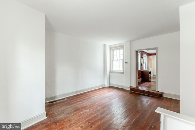 spare room with baseboards, visible vents, and hardwood / wood-style floors