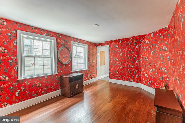 unfurnished room with wood finished floors, baseboards, and wallpapered walls