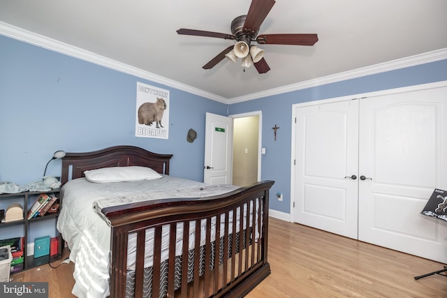 bedroom featuring light wood finished floors, baseboards, a ceiling fan, crown molding, and a closet