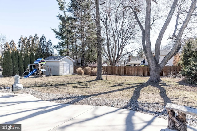 view of yard featuring an outdoor structure, a playground, fence, and a storage shed