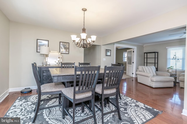 dining area with crown molding, a notable chandelier, baseboards, and wood finished floors