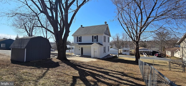 view of side of home with a shed, an outdoor structure, and fence