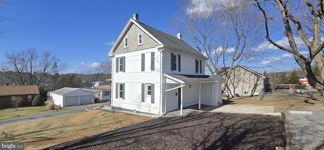 view of front of home with an outdoor structure and roof with shingles