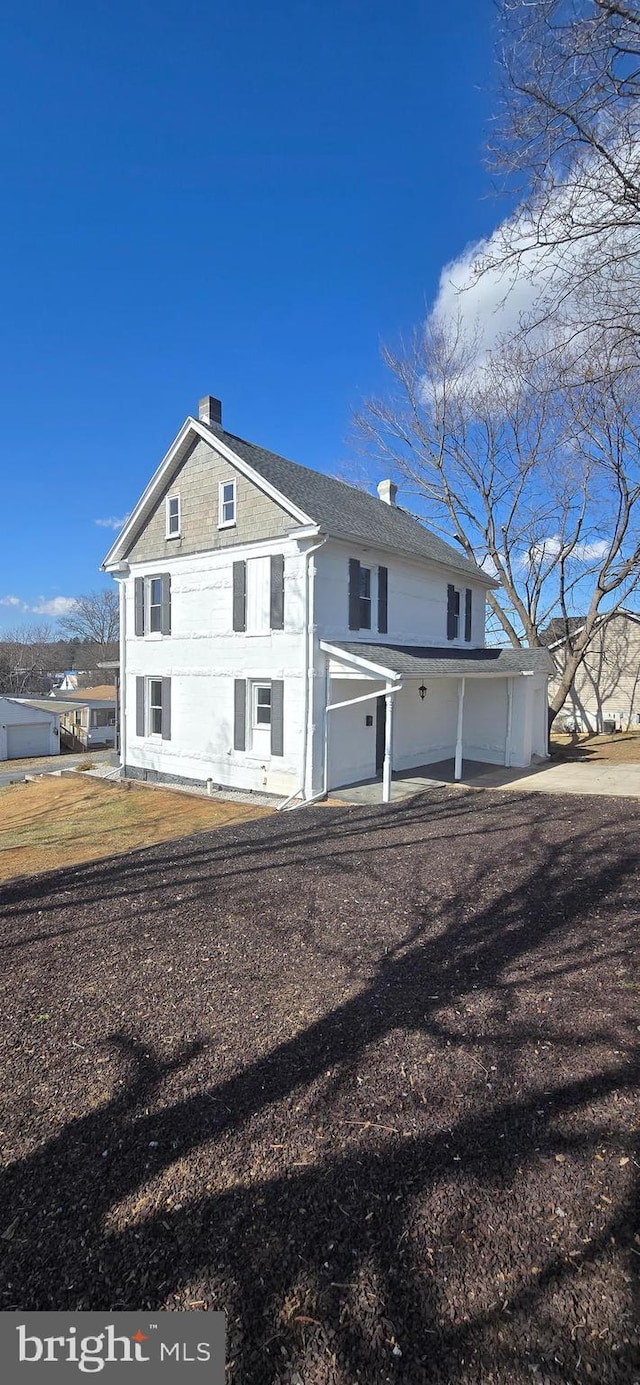 back of house with a garage and a chimney