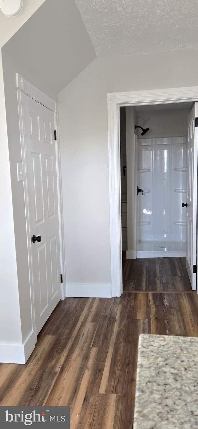 hallway with wood finished floors, baseboards, and a textured ceiling