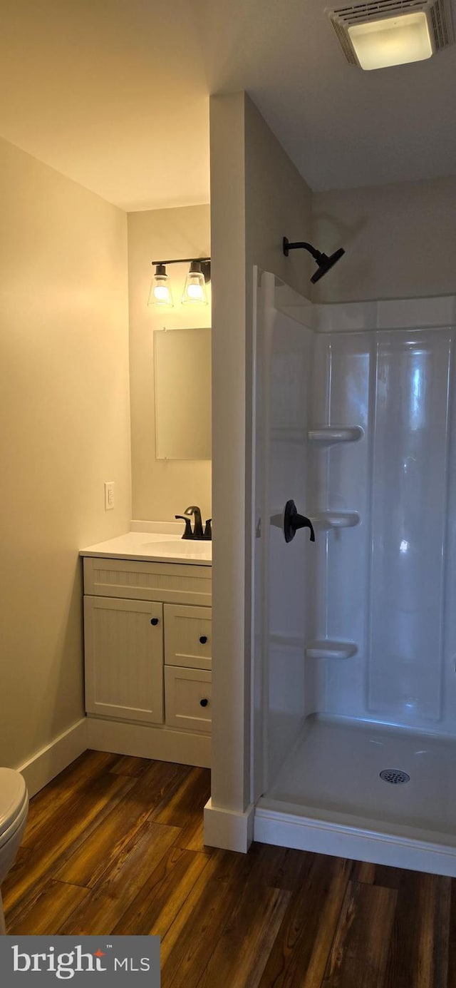 bathroom with visible vents, a shower stall, toilet, wood finished floors, and vanity