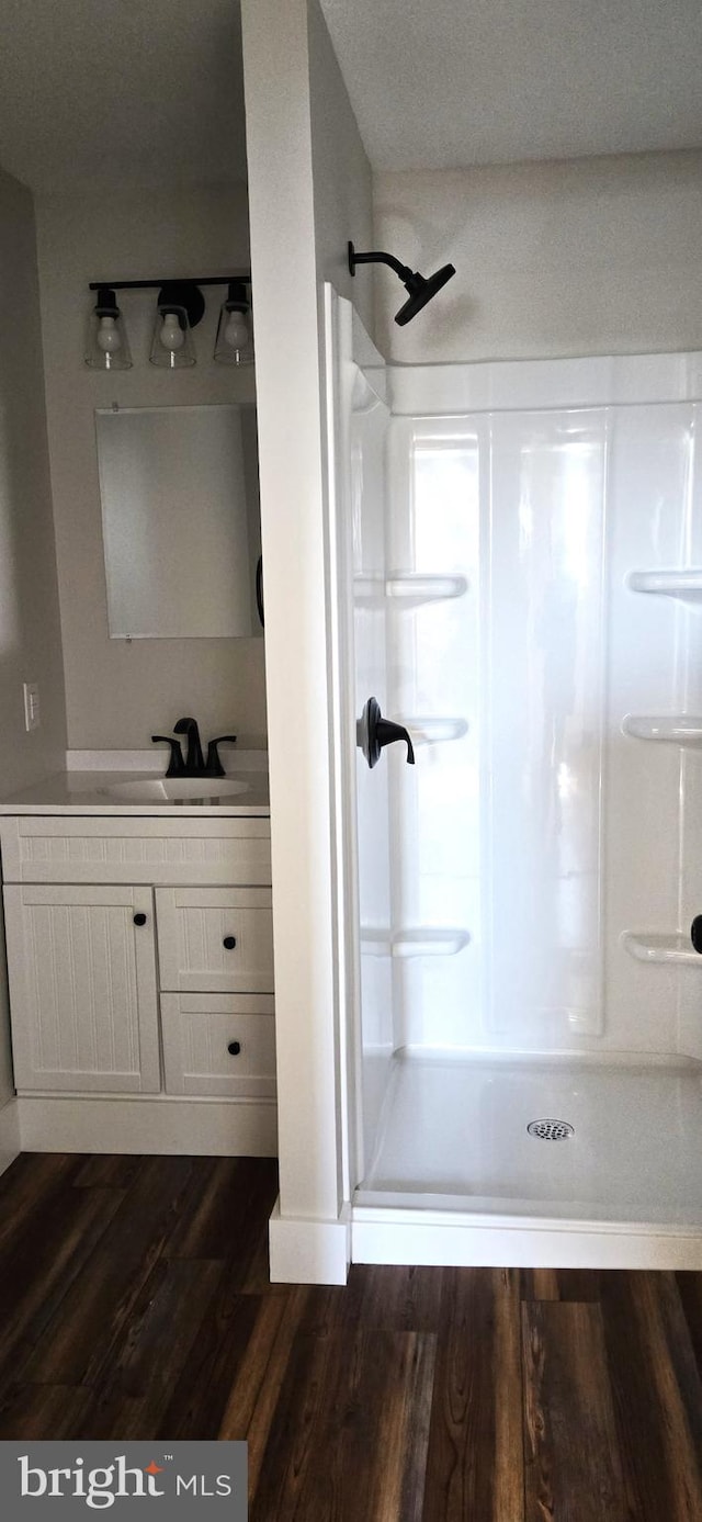 full bath featuring vanity, a shower stall, and wood finished floors