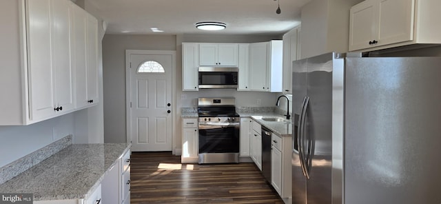 kitchen with dark wood-type flooring, light stone countertops, appliances with stainless steel finishes, white cabinetry, and a sink