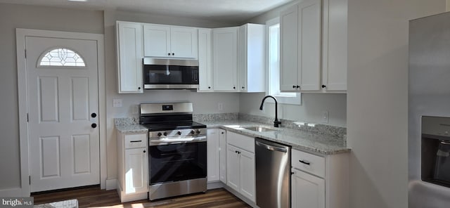 kitchen featuring light stone counters, white cabinets, appliances with stainless steel finishes, and a sink