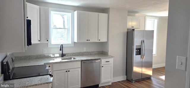 kitchen with dark wood finished floors, white cabinetry, stainless steel appliances, and a sink