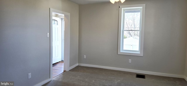 empty room with baseboards, visible vents, and carpet floors