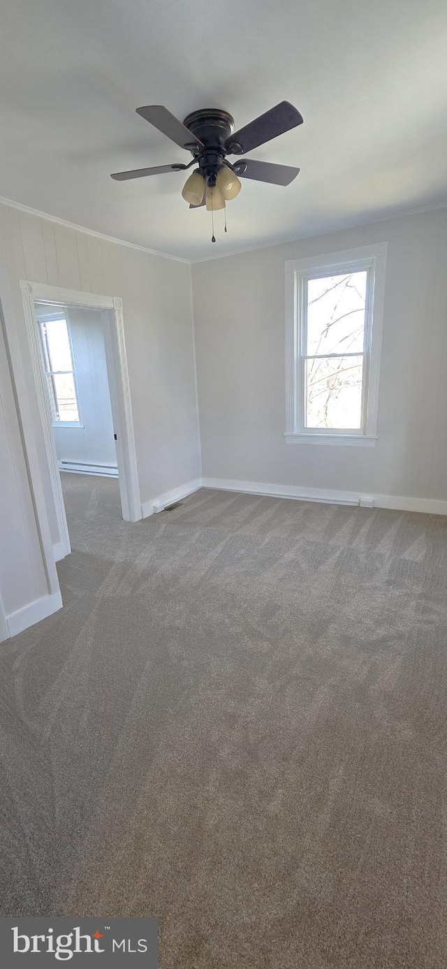 empty room with crown molding, carpet flooring, and baseboards