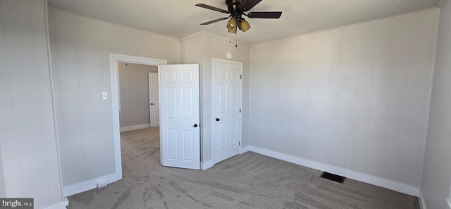 unfurnished bedroom with visible vents, ornamental molding, a ceiling fan, carpet flooring, and baseboards