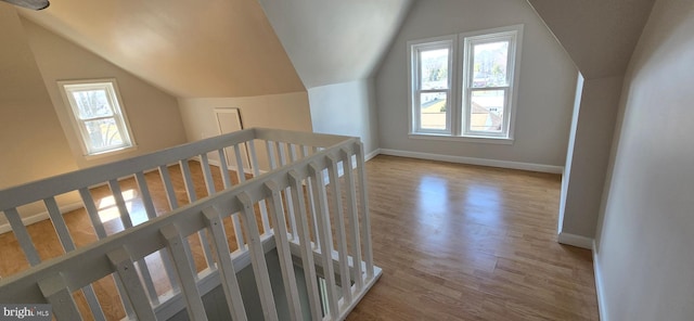 additional living space featuring baseboards, wood finished floors, and vaulted ceiling