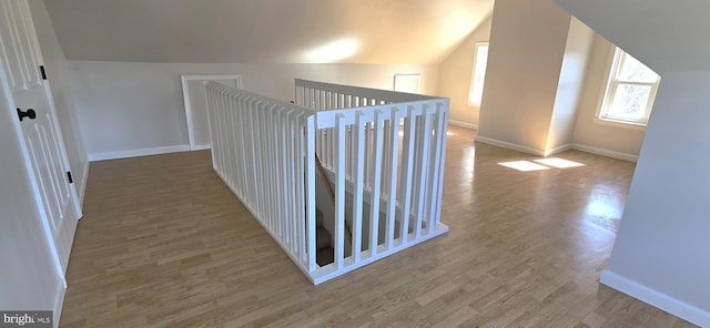 hall featuring vaulted ceiling, baseboards, and wood finished floors