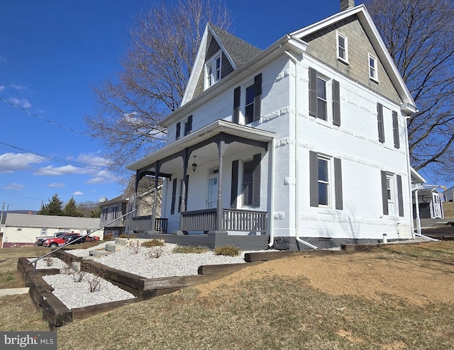 view of front facade with covered porch and a chimney