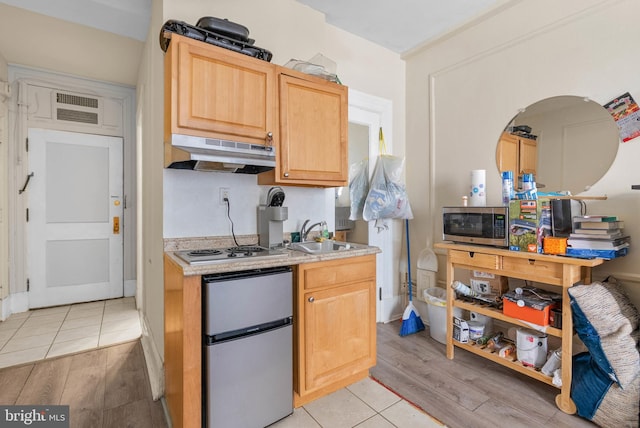 kitchen featuring visible vents, stainless steel appliances, a sink, light wood-style floors, and under cabinet range hood