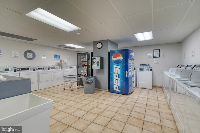 kitchen featuring light tile patterned floors, a drop ceiling, independent washer and dryer, and white cabinetry