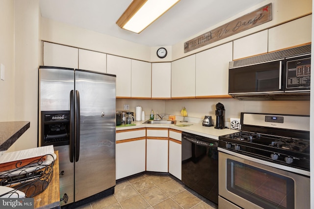 kitchen with light tile patterned flooring, a sink, black appliances, white cabinets, and light countertops