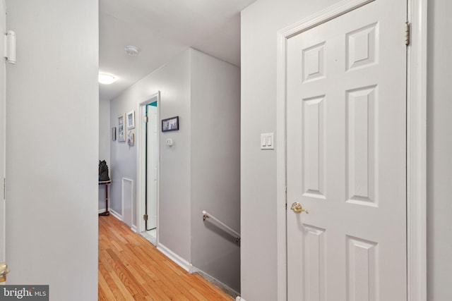 hall with an upstairs landing, light wood-style floors, and baseboards