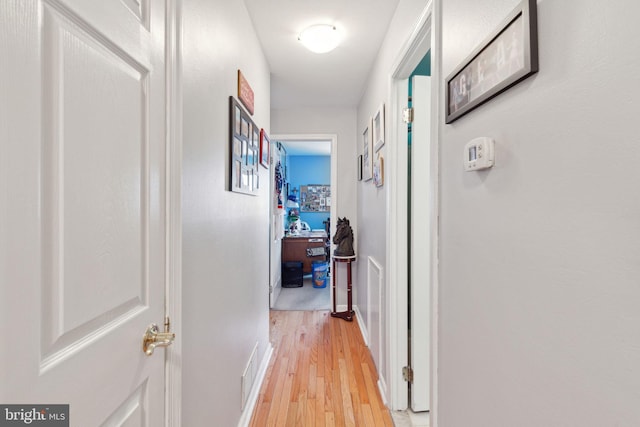 corridor with visible vents, light wood-type flooring, and baseboards