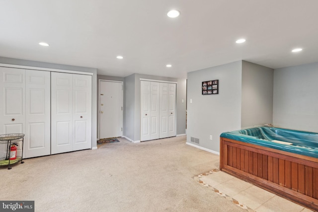 carpeted bedroom with recessed lighting, visible vents, baseboards, and two closets