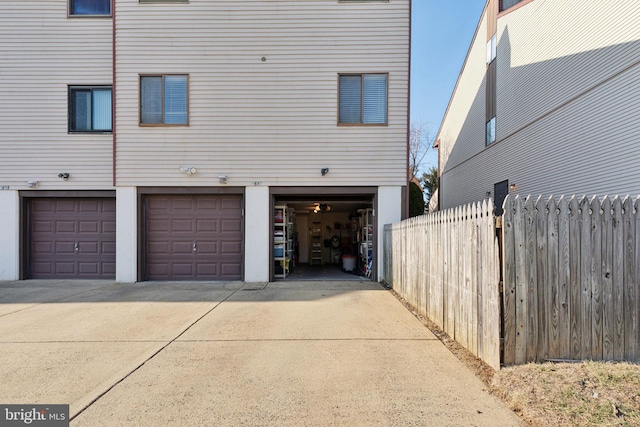 back of property featuring an attached garage, concrete driveway, and fence