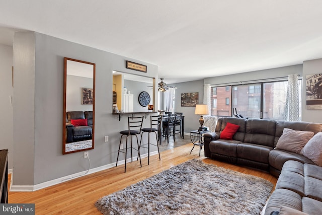 living area featuring ceiling fan, baseboards, and wood finished floors