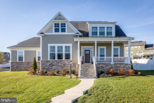 craftsman-style house featuring covered porch, roof with shingles, a front yard, and fence