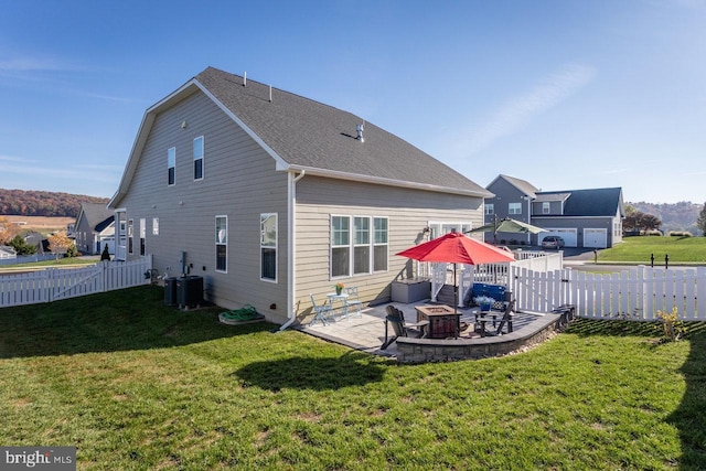 back of house featuring an outdoor fire pit, a shingled roof, a patio, a fenced backyard, and a yard