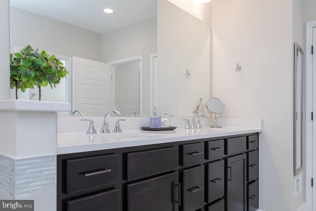 bathroom featuring double vanity, a sink, and recessed lighting