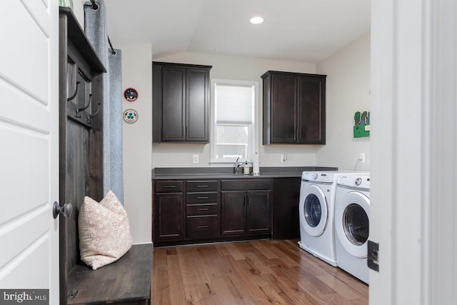 clothes washing area with recessed lighting, a sink, wood finished floors, cabinet space, and washer and clothes dryer