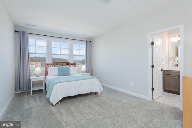 bedroom with light carpet, connected bathroom, visible vents, and baseboards