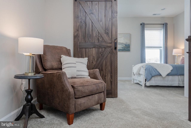 bedroom with baseboards, a barn door, visible vents, and light colored carpet