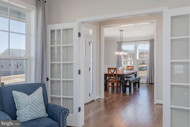 interior space featuring baseboards, ornamental molding, hardwood / wood-style flooring, and an inviting chandelier