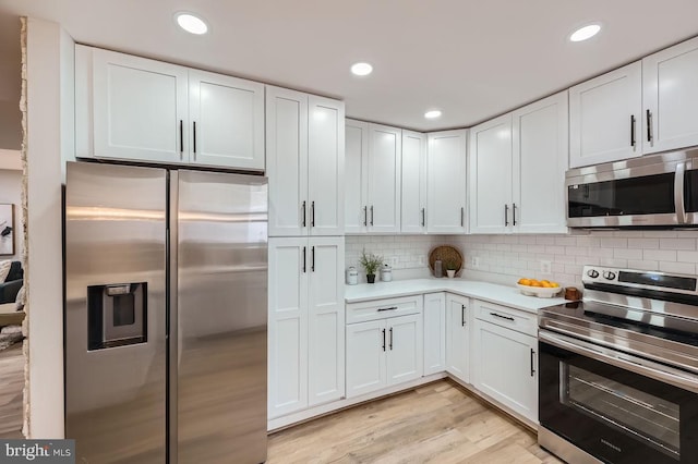 kitchen with light countertops, appliances with stainless steel finishes, decorative backsplash, and white cabinets